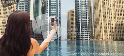 Image of woman taking selfie with smartphone over city pool