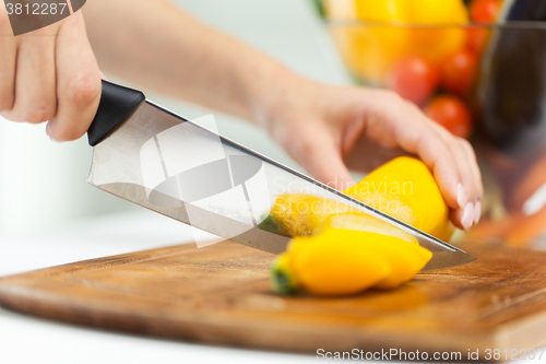 Image of close up of hands chopping squash with knife