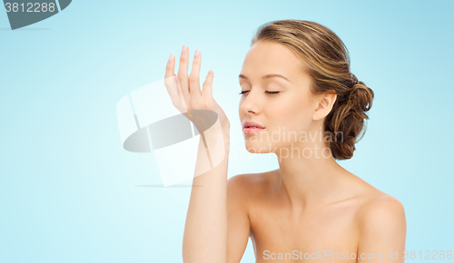 Image of woman smelling perfume from wrist of her hand