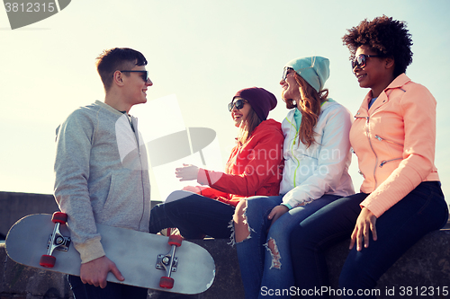 Image of happy teenage friends with longboard on street