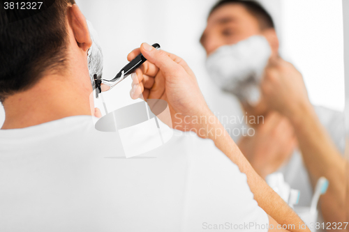 Image of close up of man shaving beard with razor blade