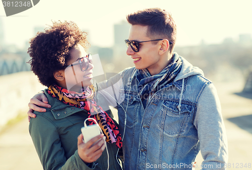 Image of smiling couple with smartphone and earphones