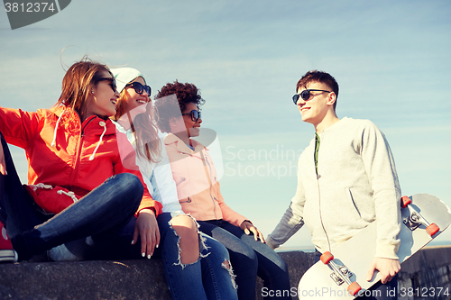 Image of happy teenage friends with longboard on street