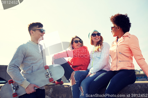 Image of happy teenage friends with longboard on street