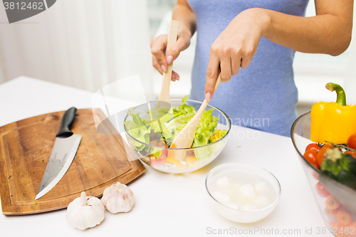 Image of close up of woman cooking vegetable salad at home