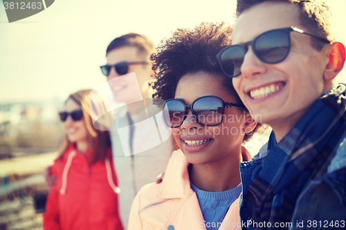 Image of happy teenage friends in shades hugging on street