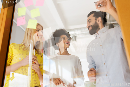 Image of happy creative team writing on stickers at office