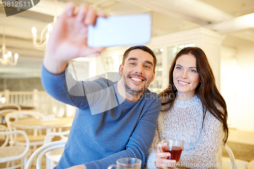 Image of couple taking smartphone selfie at cafe restaurant
