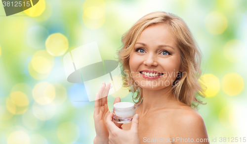 Image of happy woman applying cream to her face