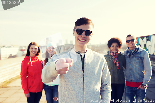 Image of happy friends pointing finger to you on street