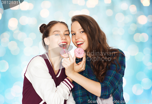 Image of happy pretty teenage girls eating donuts