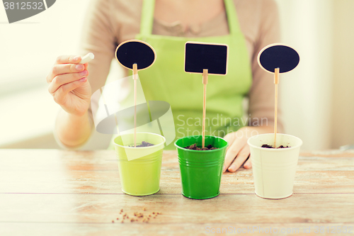 Image of close up of woman over pots with soil and signs