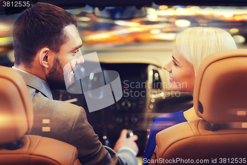Image of happy couple driving in car over night city 