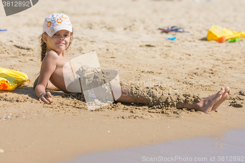 Image of Child falls asleep with wet sand lying on the beach