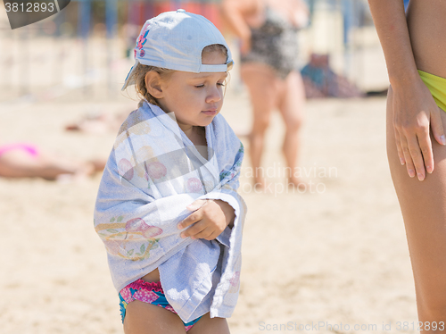 Image of The little girl is very cold bathing in the sea and basking wrapped in a towel