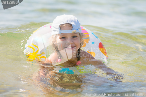 Image of Four-year girl floats with a circle in the sea water