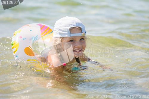 Image of Happy four-year girl floats with a circle in the sea water