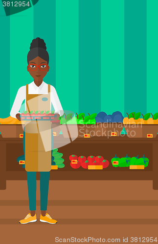 Image of Supermarket worker with box full of apples.