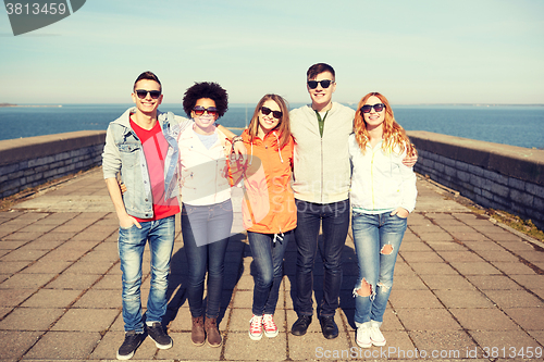 Image of smiling teenagers in sunglasses hugging on street