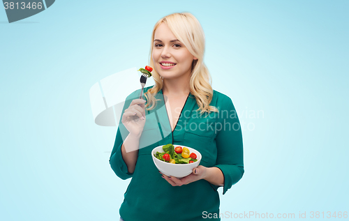 Image of smiling young woman eating vegetable salad