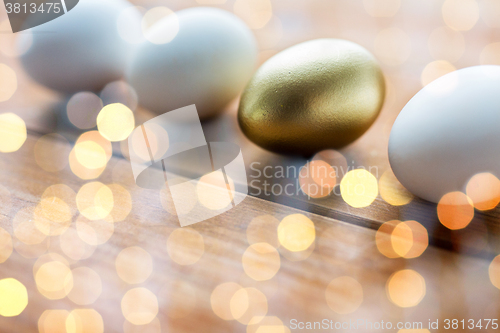 Image of close up of golden and white easter eggs on wood