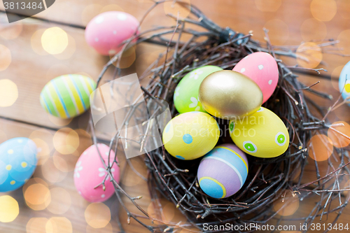 Image of close up of colored easter eggs in nest on wood