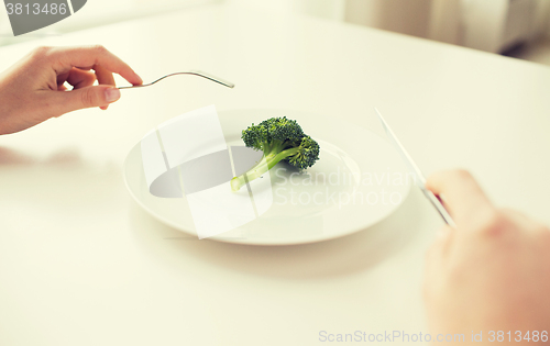 Image of close up of woman hands eating broccoli
