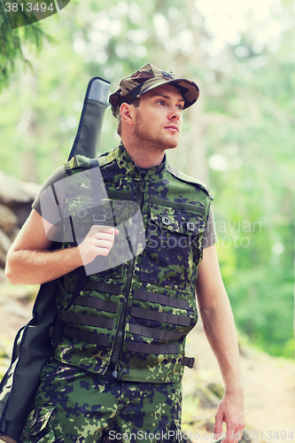 Image of young soldier or hunter with gun in forest