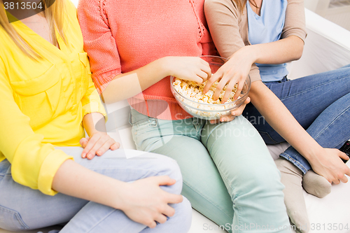 Image of close up of teenage girls eating popcorn at home