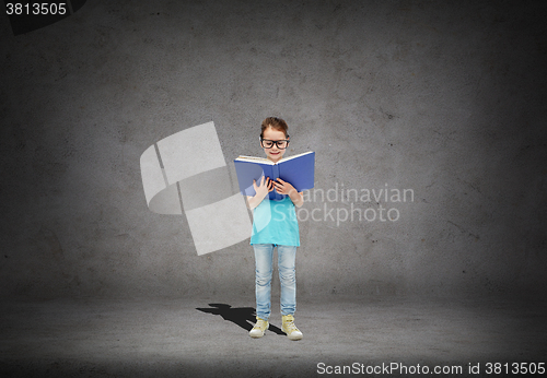 Image of happy little girl in eyeglasses reading book