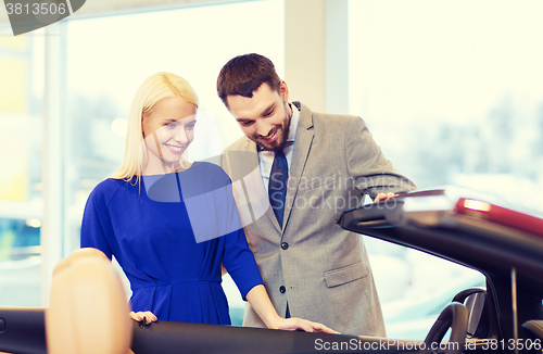 Image of happy couple buying car in auto show or salon