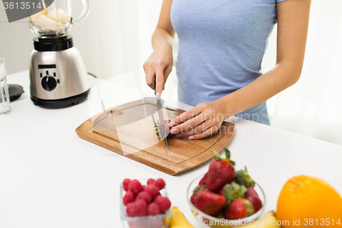 Image of close up of woman chopping strawberry at home