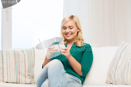 Image of happy woman with smartphone at home