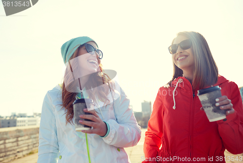 Image of happy teenage girls with coffee cups on street