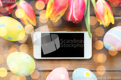 Image of close up of easter eggs, flowers and smartphone