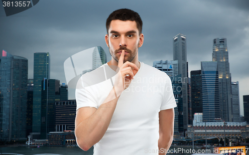 Image of man making hush sign over evening singapore city