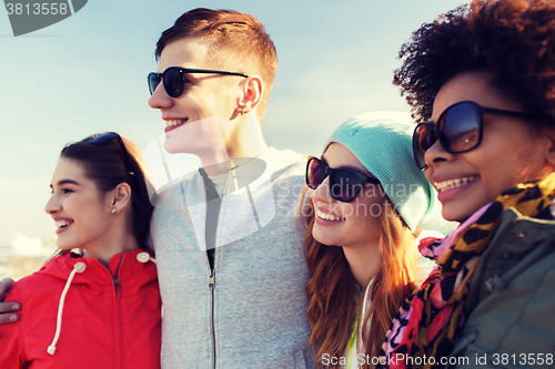 Image of happy teenage friends in shades hugging outdoors