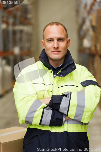 Image of man in coveralls with box at warehouse