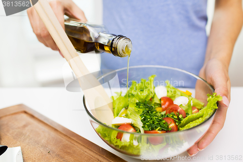 Image of close up of woman cooking vegetable salad at home