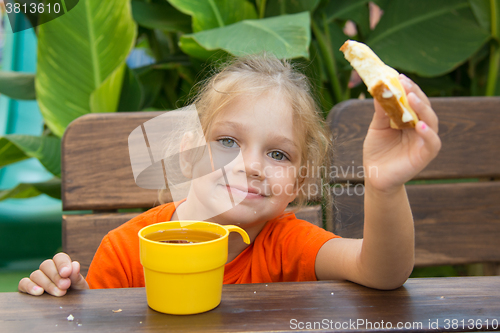 Image of  Girl smiling and eating a sandwich with tea for breakfast
