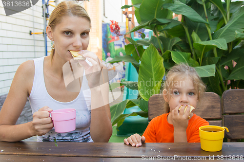 Image of Mom and daughter having breakfast with tea and sandwiches sitting on the veranda