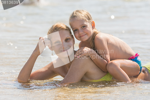 Image of Girl sitting on the mother back, which lies in the sea