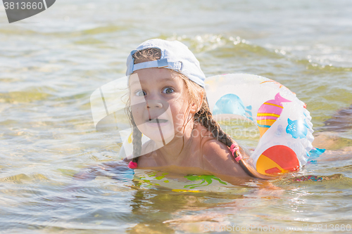 Image of Funny four-year girl floats with a circle in the water