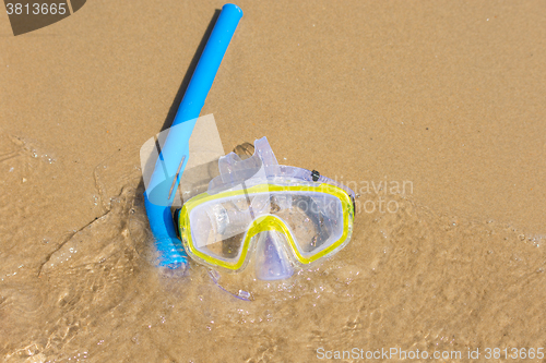 Image of The swimming mask and snorkel to breathe under water, lie on the sand at the waters edge