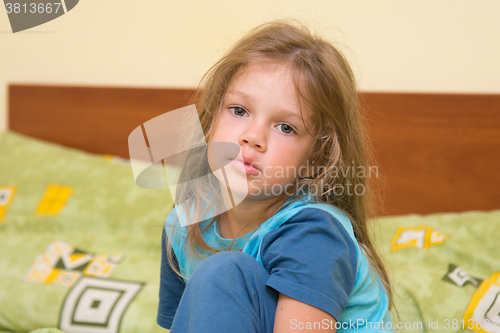 Image of Five-year girl waking up sleepy sitting on a bed