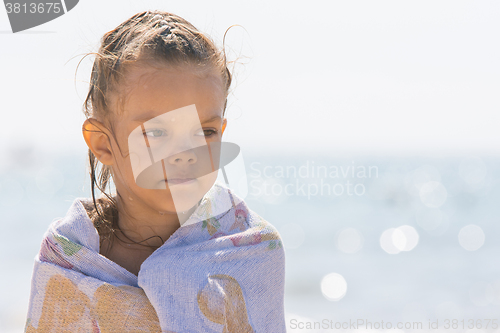 Image of Up portrait of five year old girl wrapped in a towel on the background of the sea