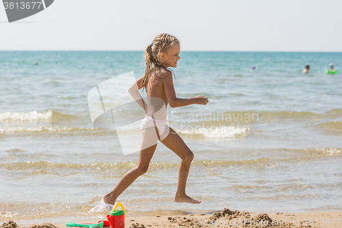 Image of Five-year girl runs along the shore of the beach at the seaside