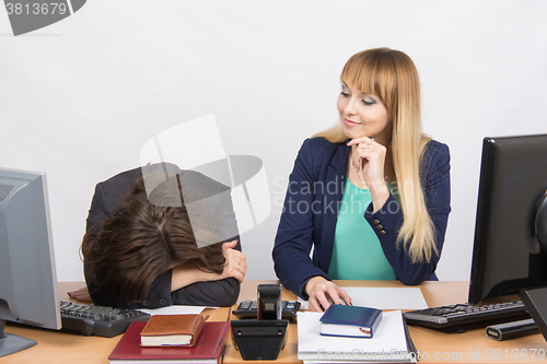 Image of The situation in office - frustrated woman lay on the table, her colleague looking at her haughtily