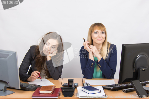 Image of The situation in the office - a woman upset looking at the document, the other happily looks into the frame