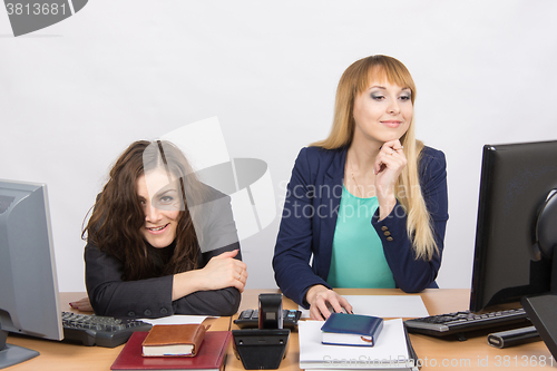 Image of The situation in the office - one girl crazy looks in the picture, her colleague looking at monitor